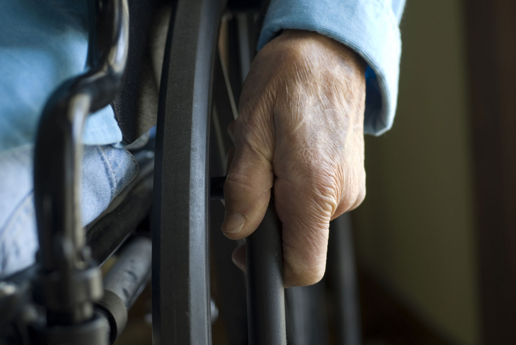 Closeup of an elderly person's hand on a wheelchair